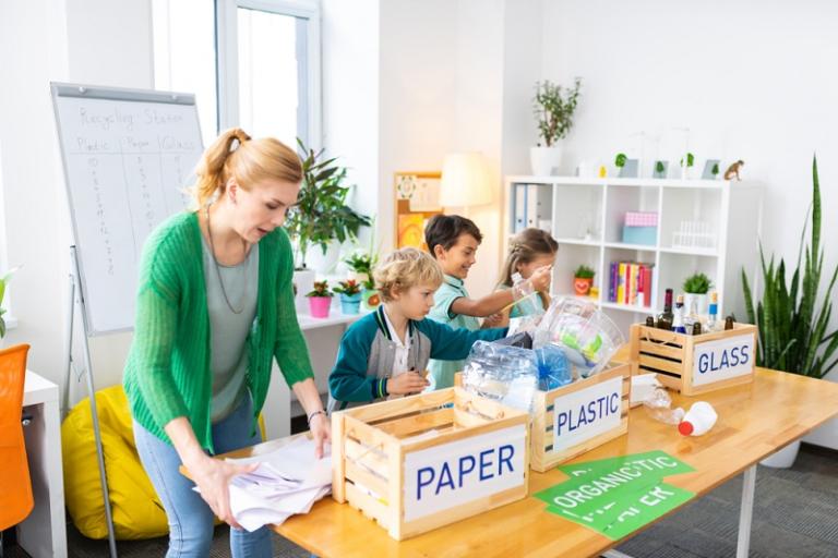 Female teacher recycling with young children