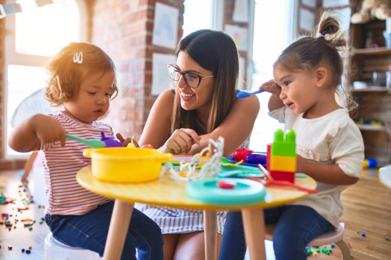 adult with two young children playing at a table